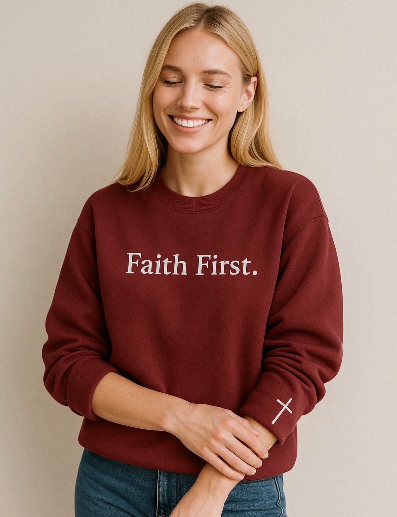 Woman wearing a maroon sweatshirt with 'Faith First.' text on a beige background