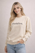 Woman wearing a beige sweatshirt with 'FaithFirst.' text on a plain background